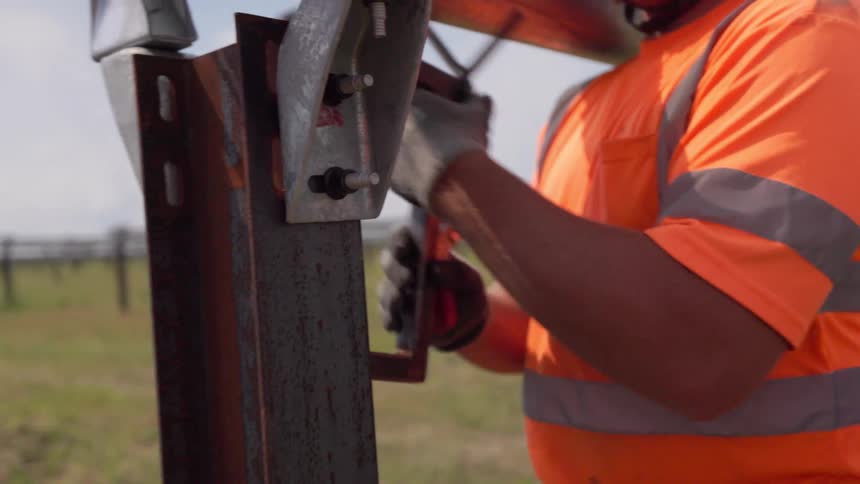 Construction worker wearing sunglasses working on a metal structure outdoors during day time