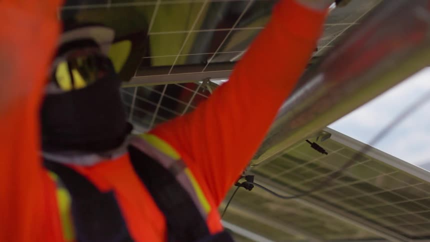 Two workers outdoors installing solar panels during day time
