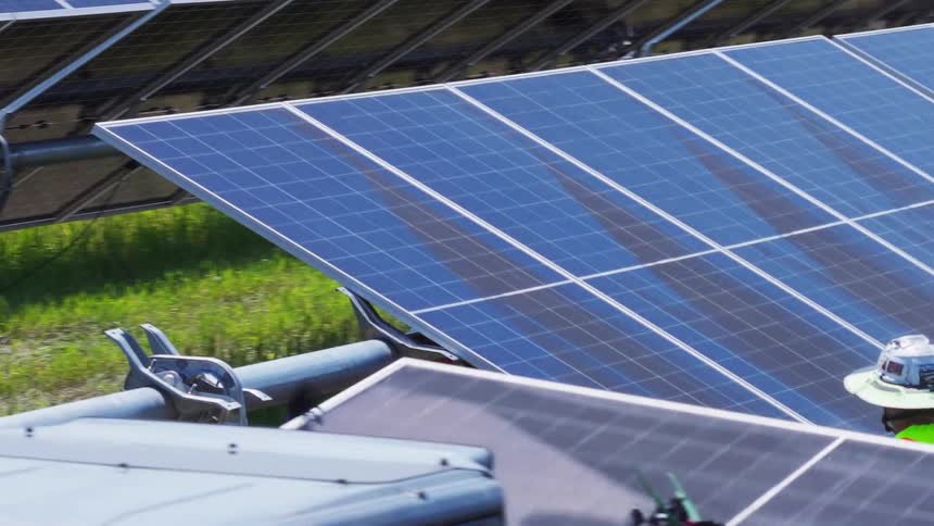 Workers carrying and installing solar panels on a field outdoors during day time