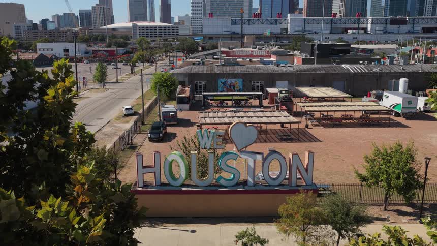The montage begins with an aerial view of a city skyline and an outdoor we love houston sign followed by scenes of solar workers collaboratively installing panels on a sunny day the sequence concludes with an interior shot of a futuristic data center