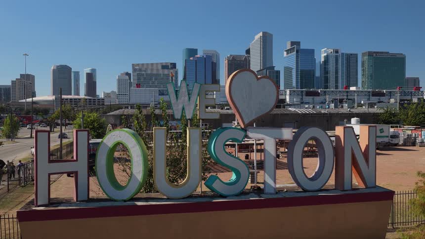 A wide establishing shot captures the we houston sign prominently placed outdoors against the backdrop of the citys modern downtown skyline on a sunny day the collection of files also features a woman arranging flowers at twilight on a hillside ca