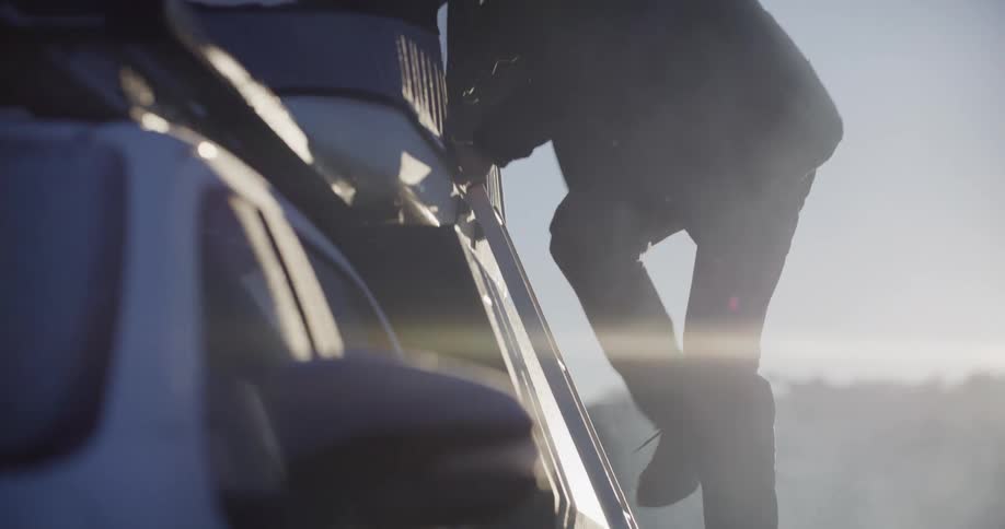 Person descends the side steps of a white vehicle under bright sunlight