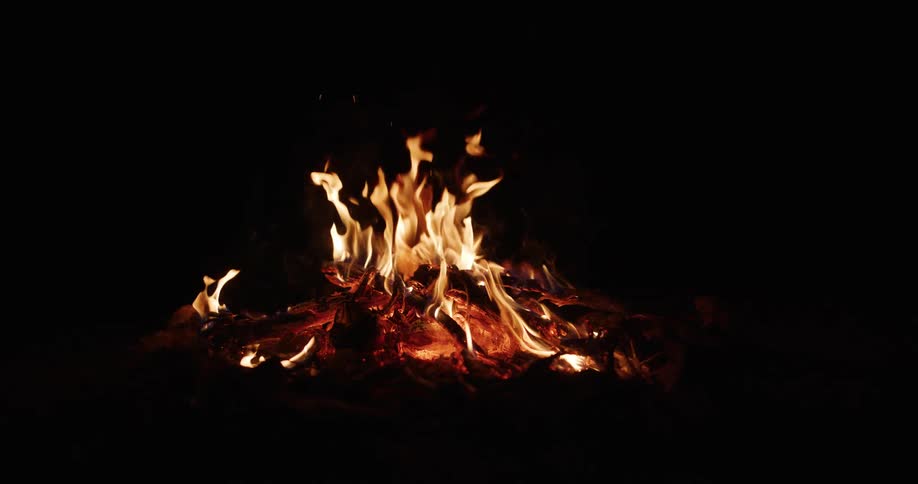 Intense fire consuming logs on the ground at night