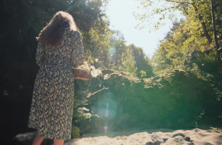 The woman puts a basket of flowers down by the rocks