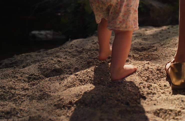 A child walking on sand near a river
