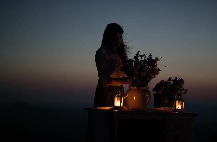 A view of a person arranging flowers next to a candle