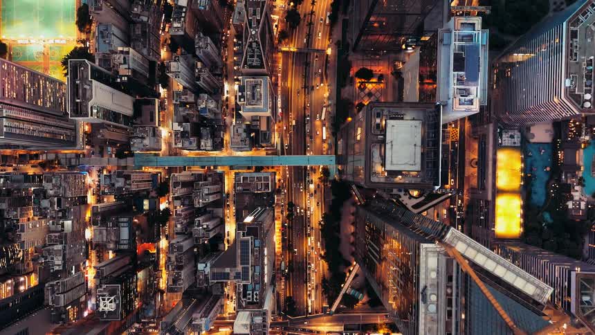 Night aerial view shows dense city with skyscrapers and symmetrically lit streets