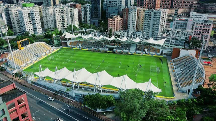 An aerial view captures a soccer match at mong kok stadium amidst the dense high rise buildings of hong kong