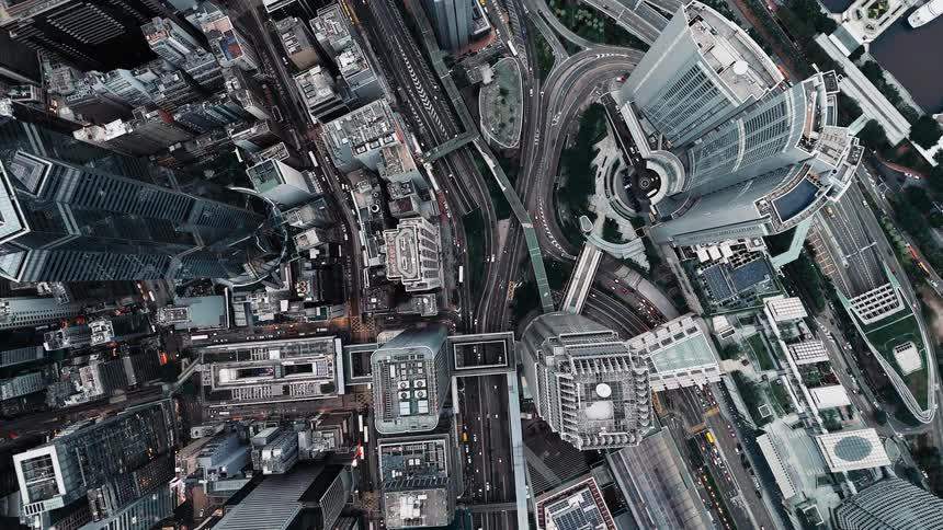 Aerial view of a metropolitan city moving over roofs of towers and skyscrapers with traffic on the highways