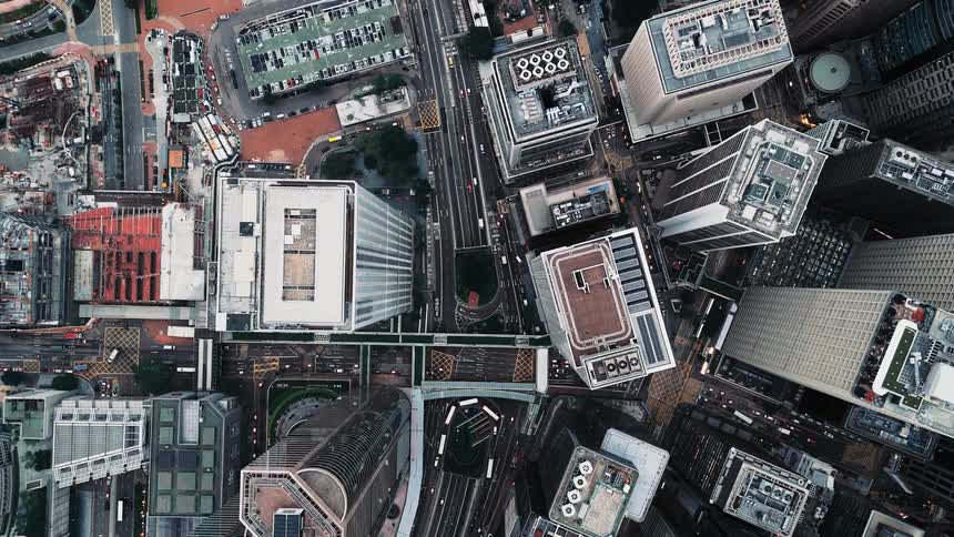 Aerial view shows modern city with tall buildings overpasses and skybridges connecting urban structures