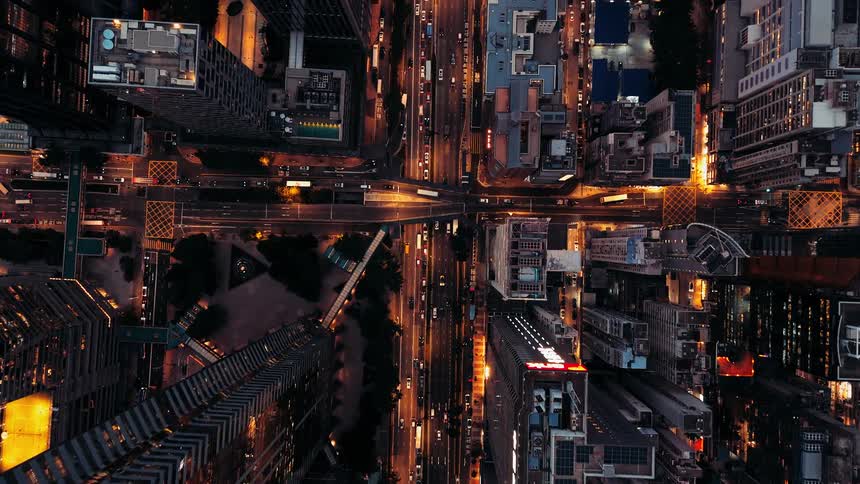 Symmetrical aerial view of city at night with lit streets and varied buildings