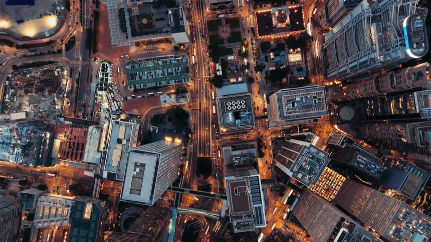 Urban intersection lit by night lights surrounded by skyscrapers