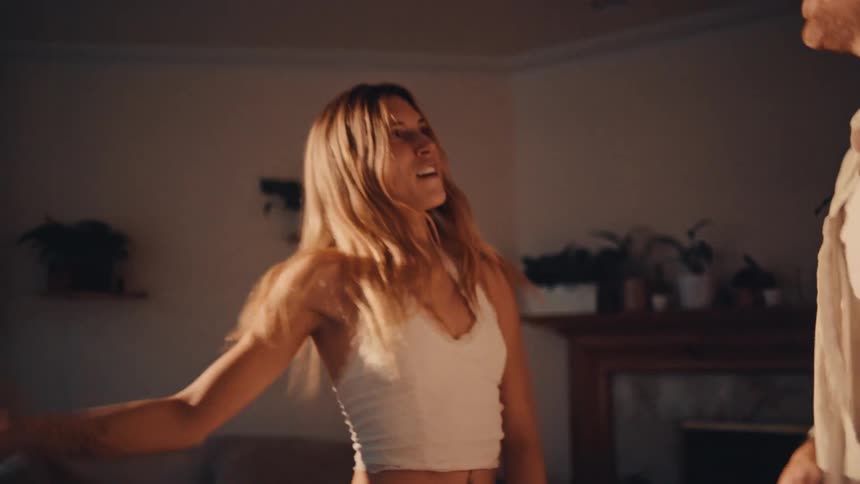 Couple smiles while dancing together in their living room
