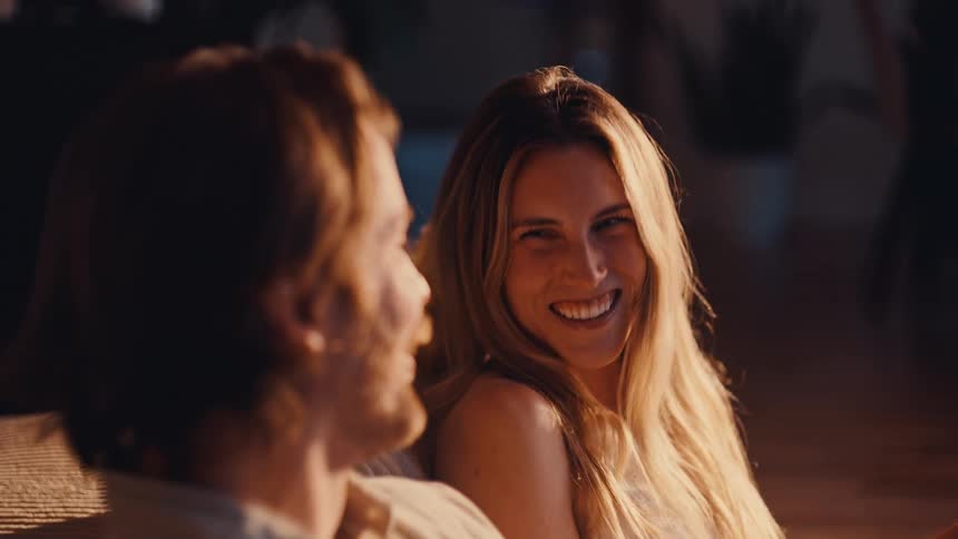 Woman smiling at a man as they sit in a sunlit indoor setting