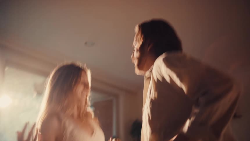 A happy couple dances playfully together in a sunlit living room
