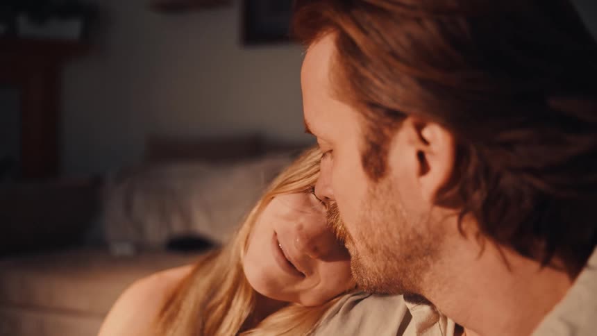 The man kisses a woman on the forehead