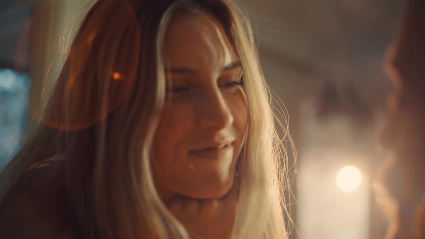 A woman is shown smiling softly and warmly at someone offcamera her long blonde hair catching the lightthe man then kisses her forehead gently before looking up with a loving content expression