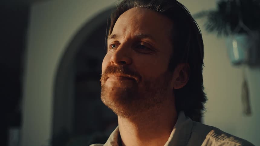 Man in a closeup lit by sunlight inside an indoor setting