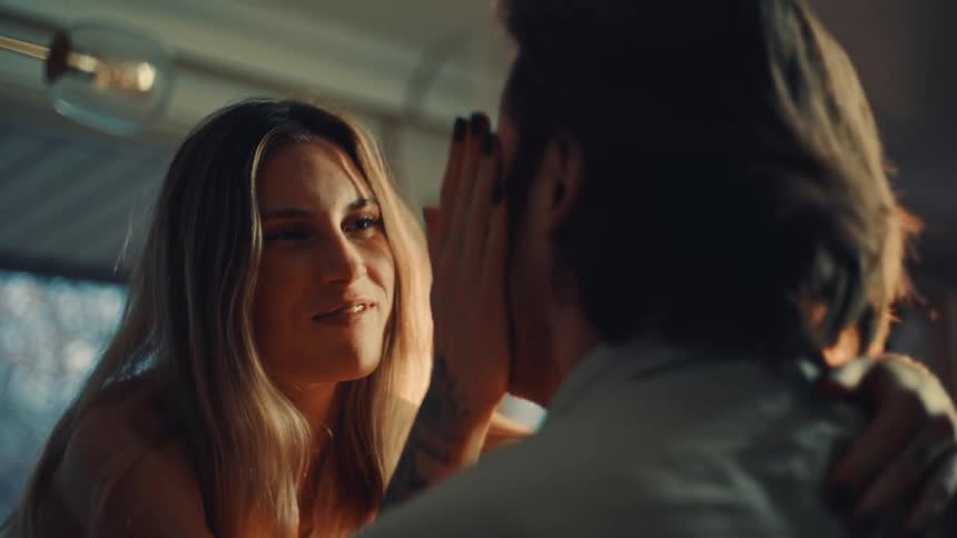 Couple shares intimate moment with warm smile and gentle touch under cozy lighting