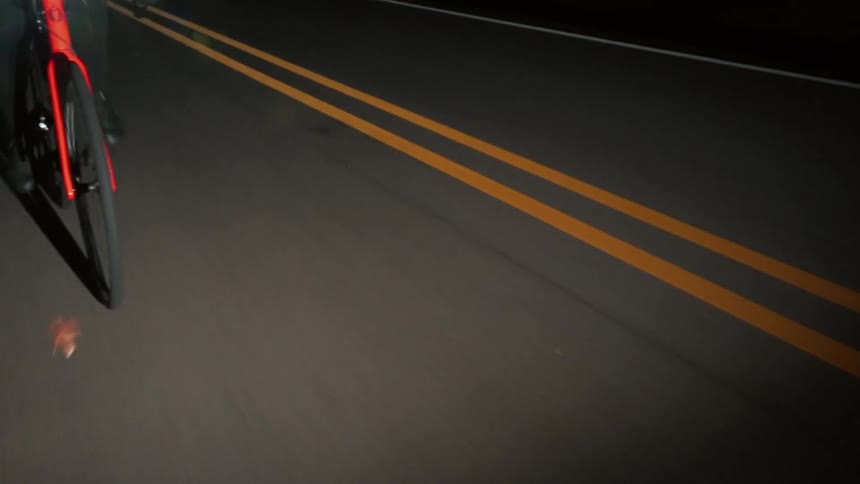 The man is cycling on the road at night