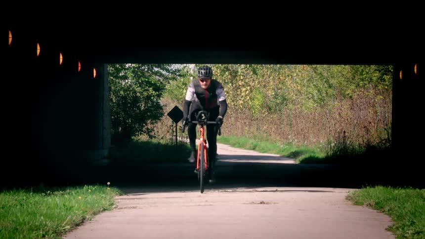 The cyclist races under the overpass