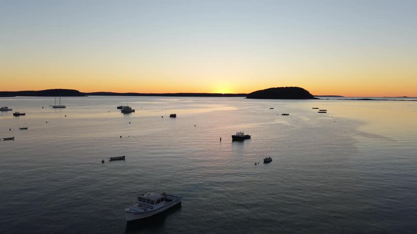 Boats are anchored near the shore at sunrise