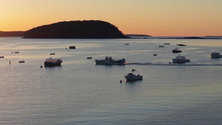 Boat sails across the water as other boats sit idle