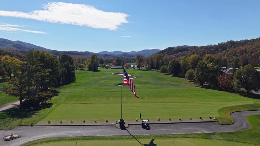 Golf course with a us flag at the center surrounded by carts and green areas