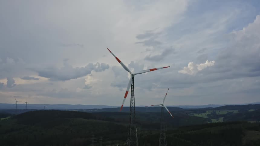 Red and white windmills are turning in a mountainous area