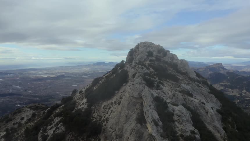 Scrub dotted mountains tower over rough foggy terrain on an overcast day