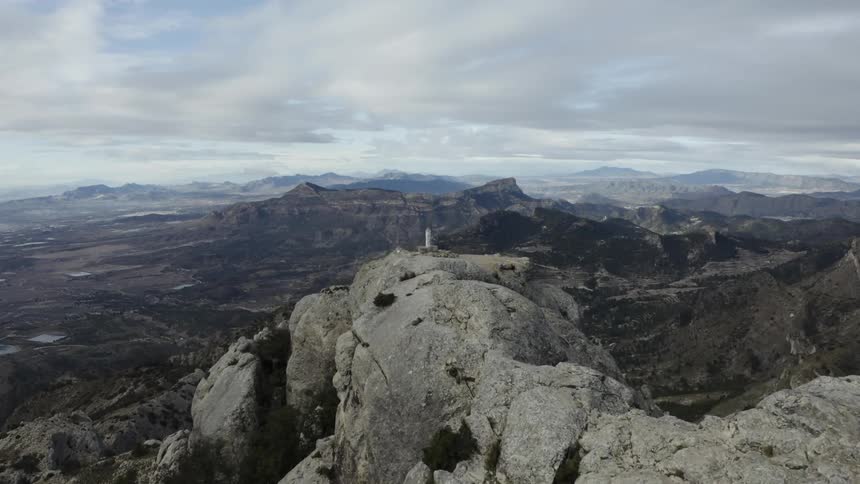 Natural landscape with many rocky mountains and valleys with a white tower on the peak of one of the mountains outdoors during day time