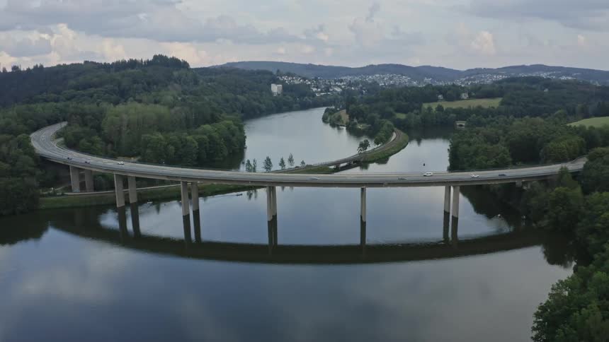 Traffic crosses the water outside a town on a raised highway on a summer day