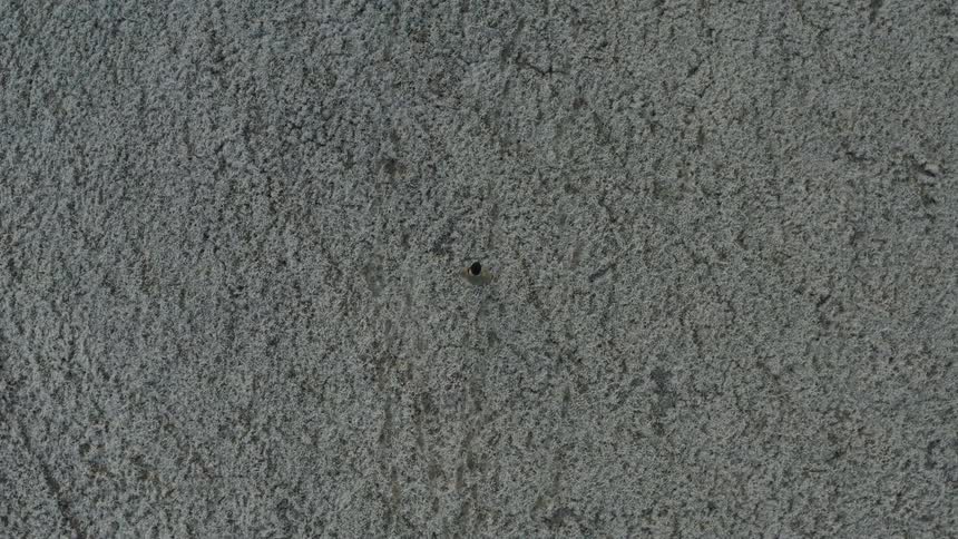 Man walks across flat textured terrain during the daytime