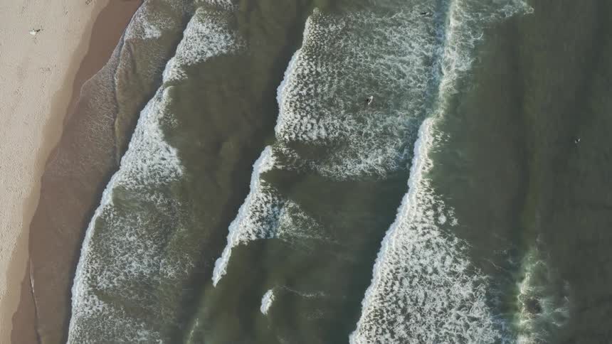 Rows of waves land on the sandy shore