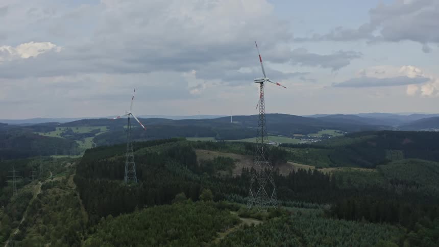 A view of some power generating windmills at the top of hills