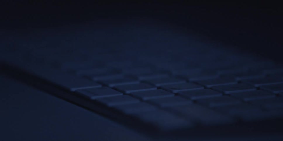 A flickering light reveals a keyboard in a dark room