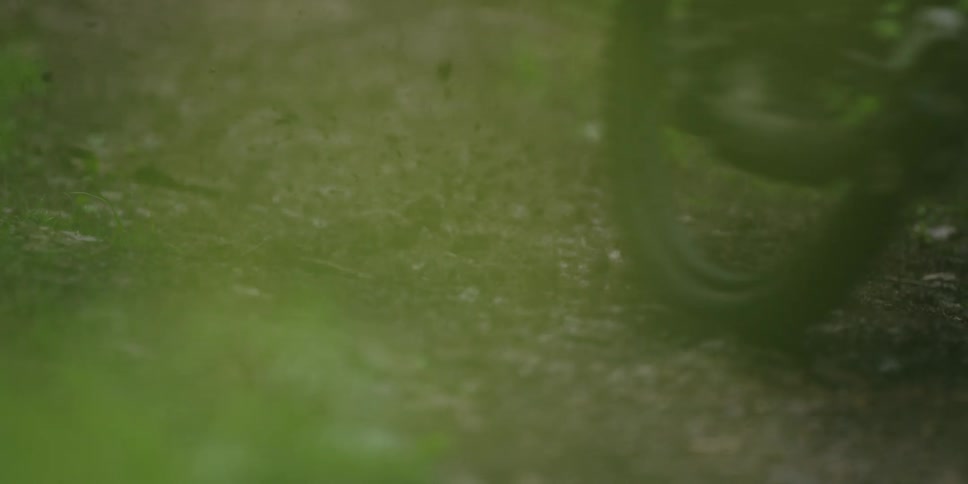 This very brief video clip features a closeup lowangle shot of a tire rolling over a dirt or gravel paththe tire is likely from a bicycle or motorcycle and the path is surrounded by greenery suggesting a setting in a wood or forest