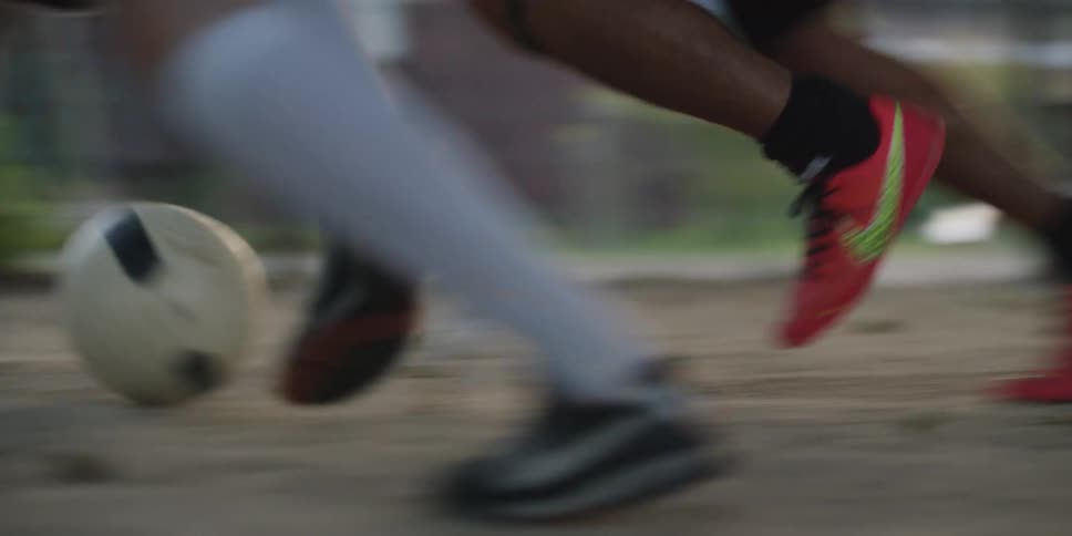 Players move ball on sandy surface during informal match