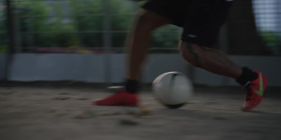 In a dynamic fastpaced game a players feet expertly dribble a soccer ball past multiple defenders on a dusty urban court