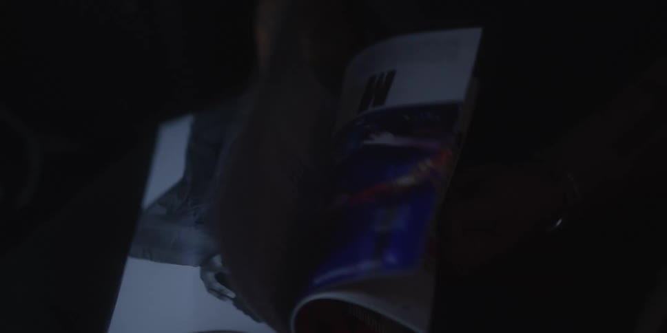 Person flips through illustrated publication with vibrant colors in dark setting