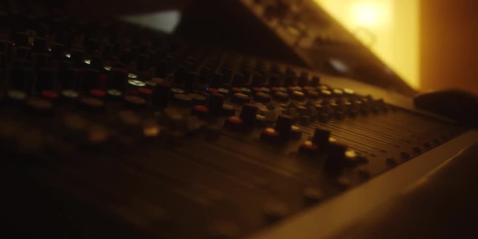 A close up of a black audio mixer in dim lighting