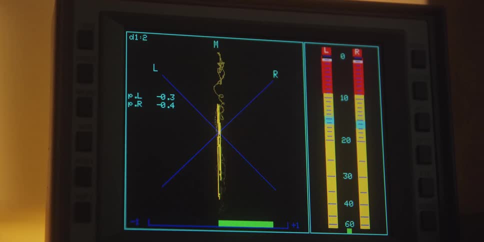 Closeup of an audio monitor screen displaying live sound wave visuals and level meters
