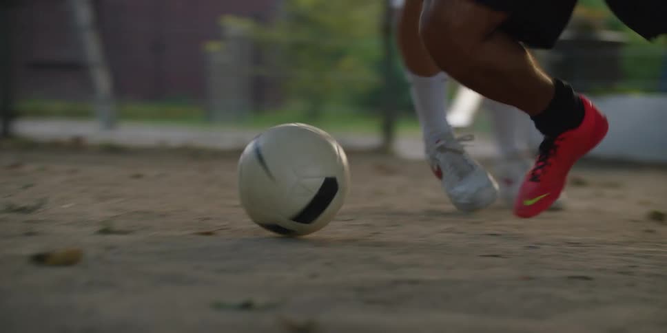 On a dusty court one players feet skillfully dribble a soccer ball past a defender in a fastpaced game
