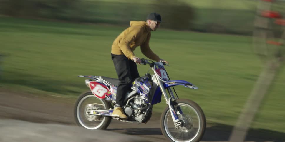 The man speeds on his dirt bike in hte park