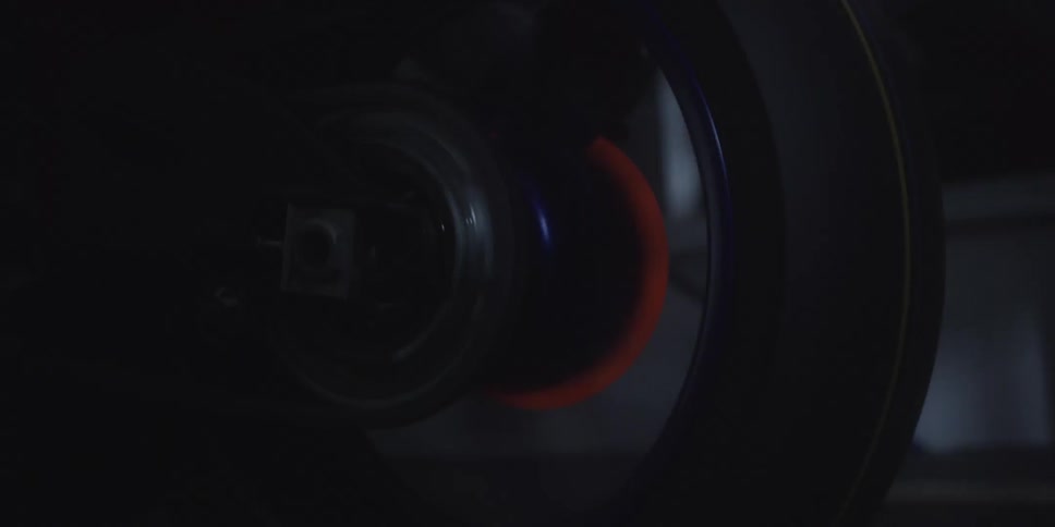 This video shows a closeup of a rotating wheel likely on a motorcycle in a very dark setting the brake disc is glowing a bright orangered color due to extreme heat from friction visible behind the dark silhouette of the tire