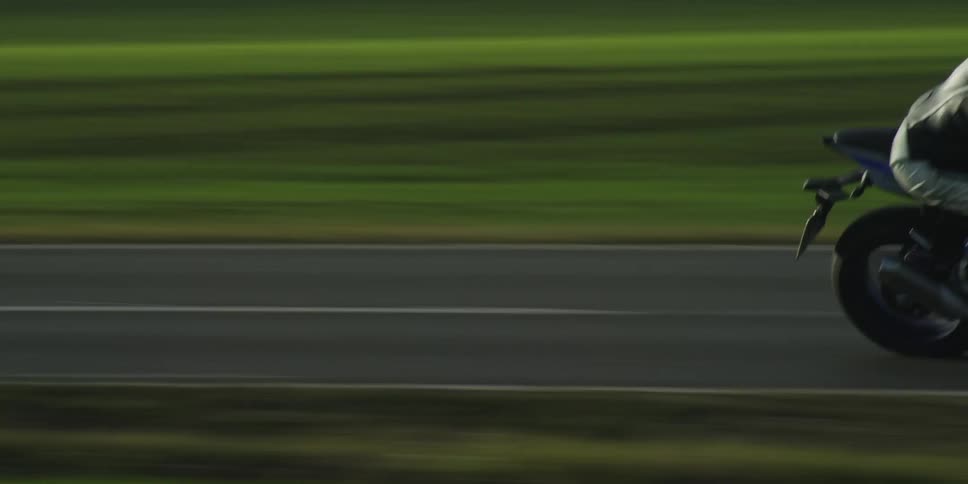 Motorcycle traveling fast as a truck passes by on the other side of the road