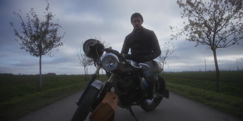 Classic motorcycle parked on rural road with wind turbines in the background