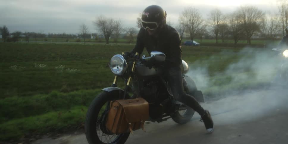Motorcyclist performing a burnout with smoke coming from the tire on a rural road