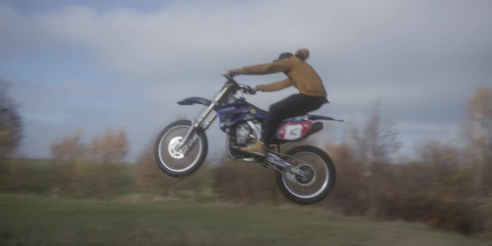 The man jumps on the hill with his dirt bike