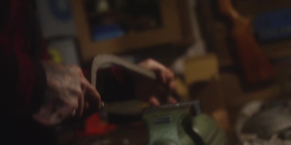 Close up of a man cutting a metal bar with a saw in a workshop